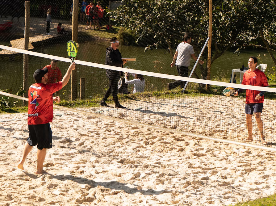 Criança jogando beach tennis na quadra cercada de verde