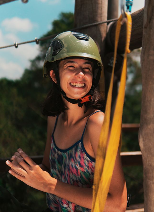 Menina de capacete sorrindo na plataforma da tirolesa