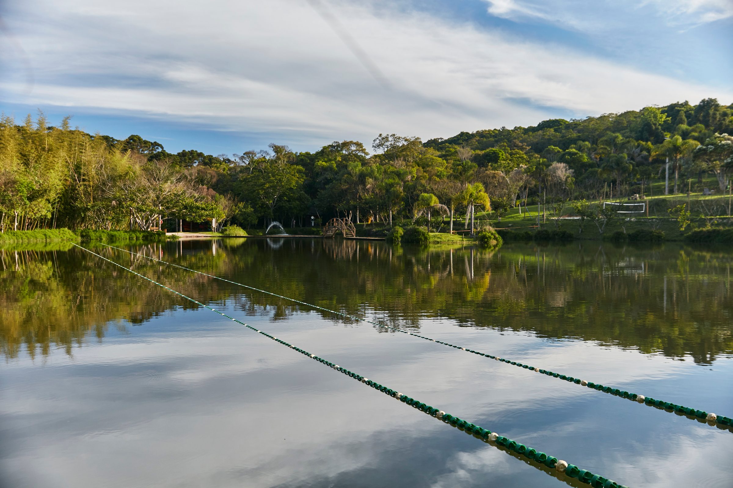 Lago da Reserva com a ponte de madeira e a mata refletida na água