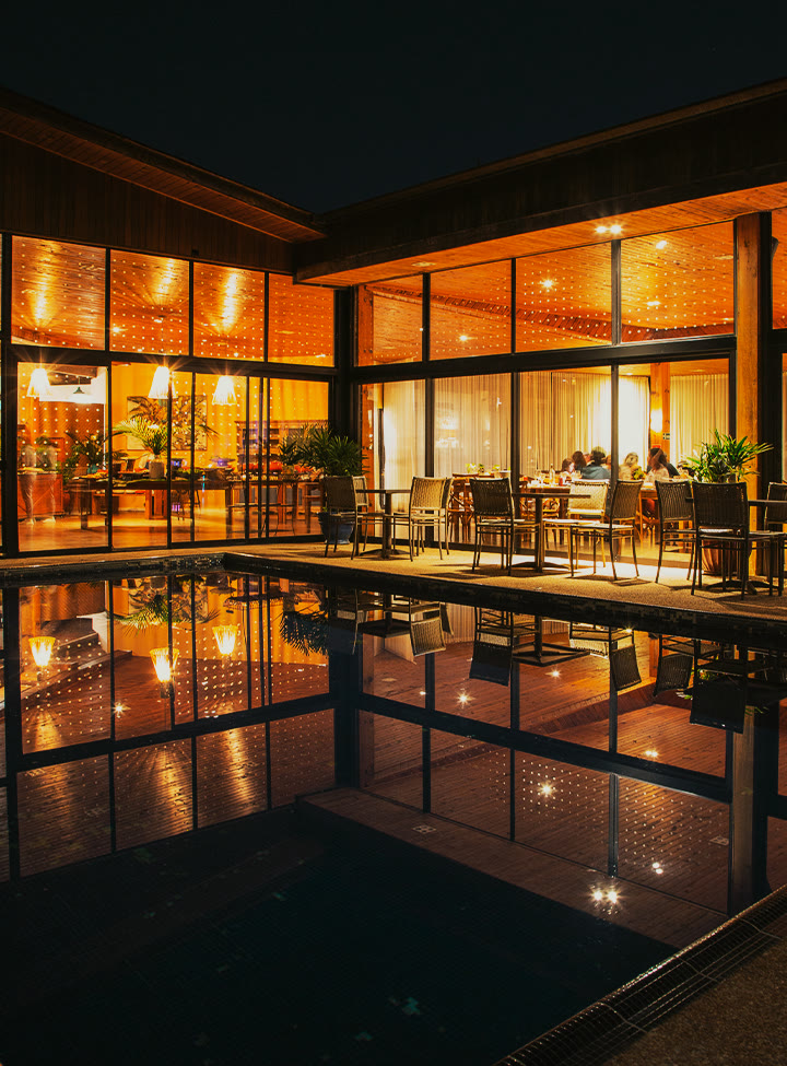 Restaurante iluminado à noite refletido na piscina